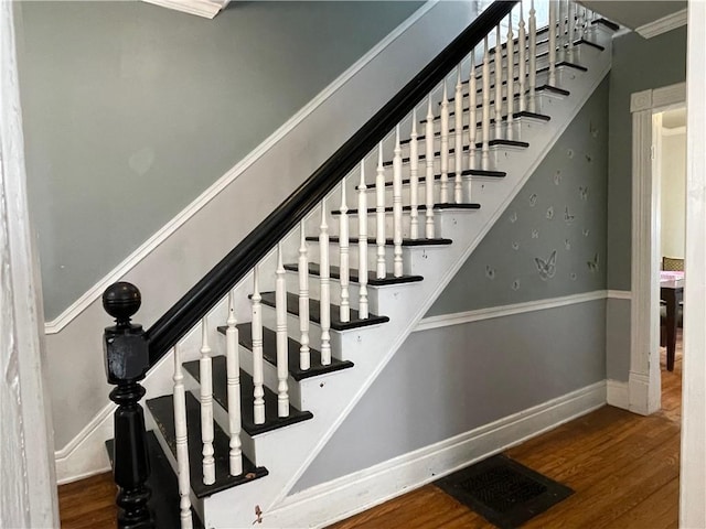 staircase with baseboards, visible vents, and wood finished floors