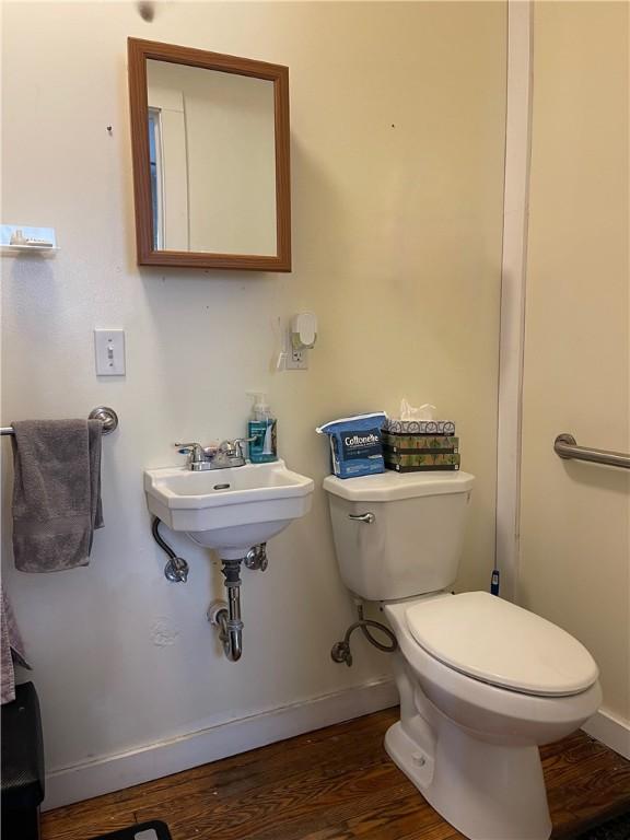 half bathroom featuring toilet, wood finished floors, and baseboards