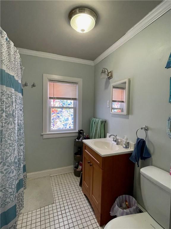 bathroom with vanity, crown molding, toilet, baseboards, and curtained shower