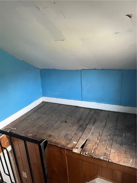 additional living space with hardwood / wood-style flooring, baseboards, and vaulted ceiling