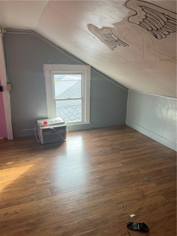 additional living space featuring a wall mounted air conditioner, vaulted ceiling, and wood finished floors