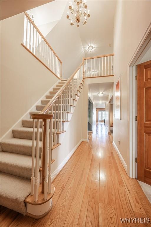 7131 Lakeshore Ter, Newfane, NY 14008 - entryway with stairs, a high ceiling, a notable chandelier, and wood finished floors