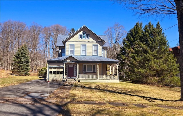 victorian house with driveway, covered porch, a garage, and a front yard