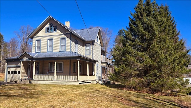 exterior space featuring a chimney, a garage, a shingled roof, a porch, and a yard