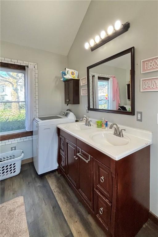full bath with vaulted ceiling, independent washer and dryer, wood finished floors, and double vanity