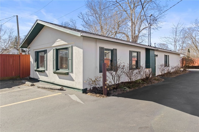 280 S Main St, Canandaigua-City, NY 14424 - view of home's exterior with stucco siding, fence, and uncovered parking