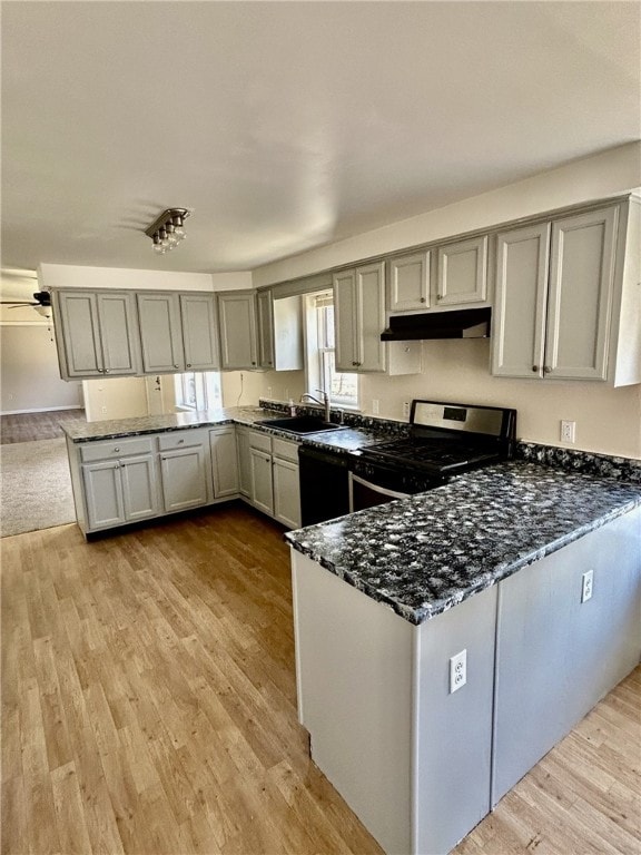 kitchen with gray cabinets, under cabinet range hood, a peninsula, and stainless steel gas stove
