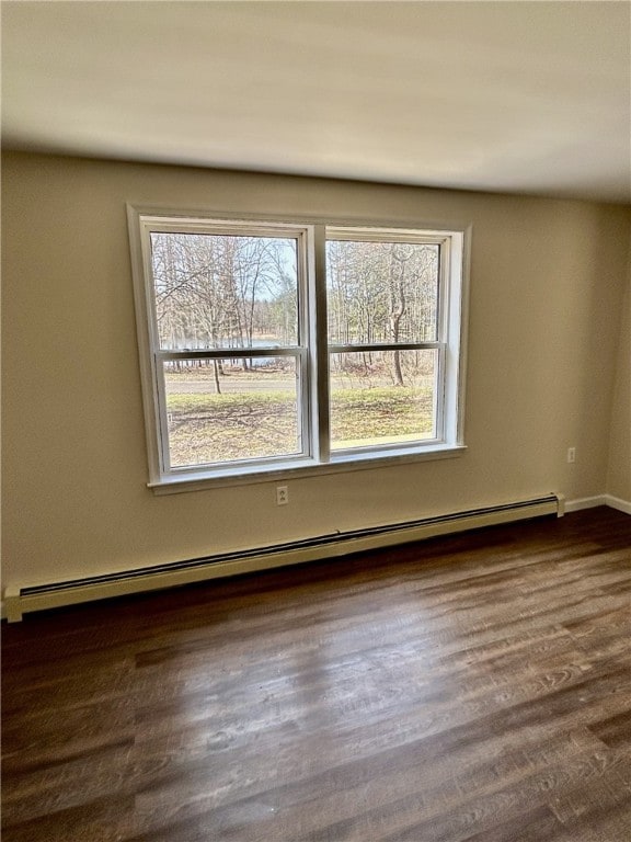 unfurnished room with baseboards, baseboard heating, dark wood-style flooring, and a healthy amount of sunlight