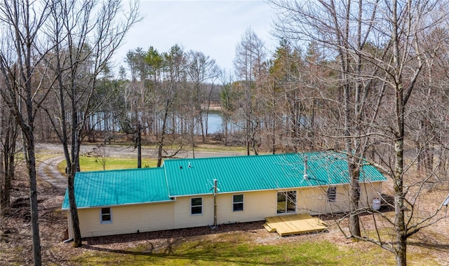 back of property featuring metal roof, a wooden deck, and a yard
