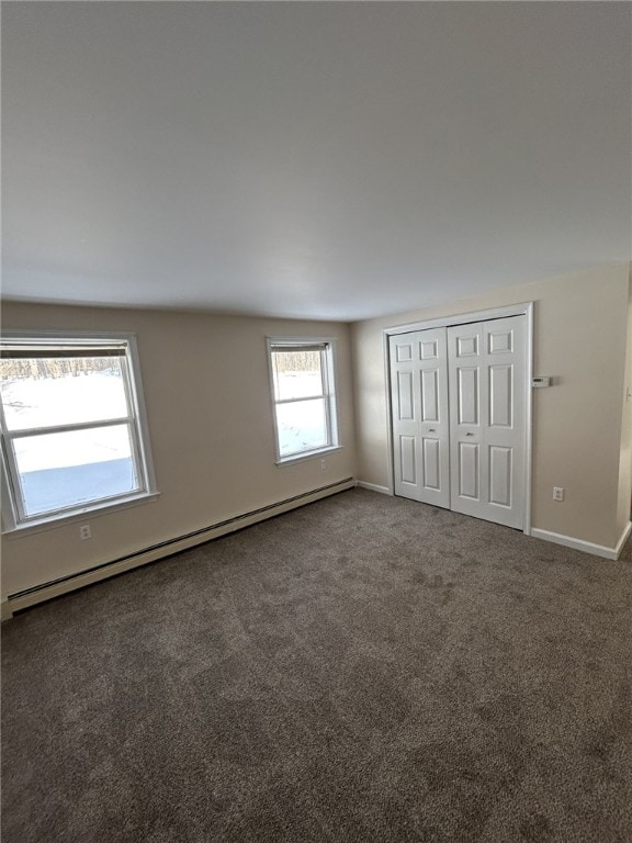 unfurnished bedroom featuring baseboards, a closet, a baseboard heating unit, and carpet flooring