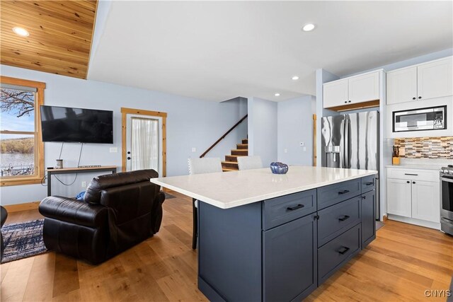 2310 Olanco Rd, Spafford, NY 13110 - kitchen with appliances with stainless steel finishes, white cabinetry, open floor plan, light countertops, and light wood-type flooring