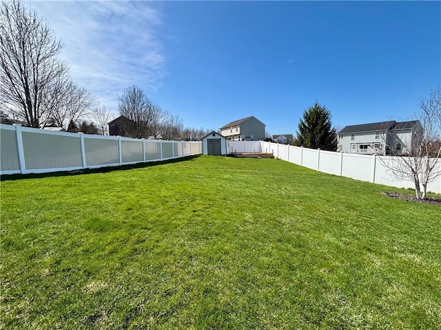 view of yard with a fenced backyard, an outdoor structure, and a storage shed