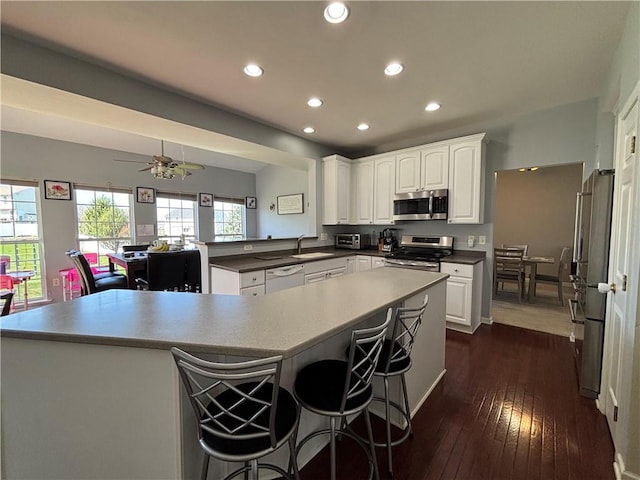 kitchen featuring dark wood-type flooring, white cabinetry, a sink, and stainless steel appliances