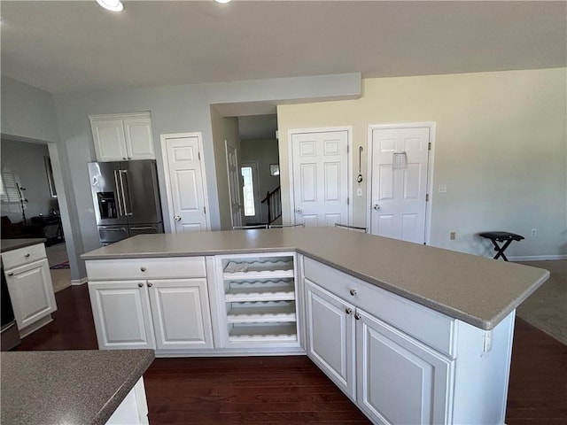 kitchen with white cabinets, high end fridge, a center island, and dark wood finished floors