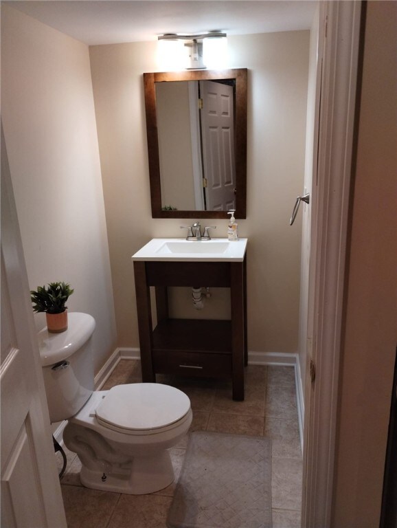 bathroom with baseboards, toilet, tile patterned flooring, and vanity