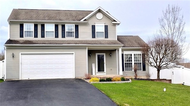 traditional-style home with aphalt driveway, fence, a shingled roof, and a front yard