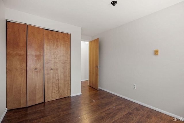 unfurnished bedroom with wood finished floors, baseboards, and a closet