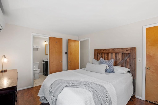 bedroom with wood finished floors, ensuite bath, and baseboards