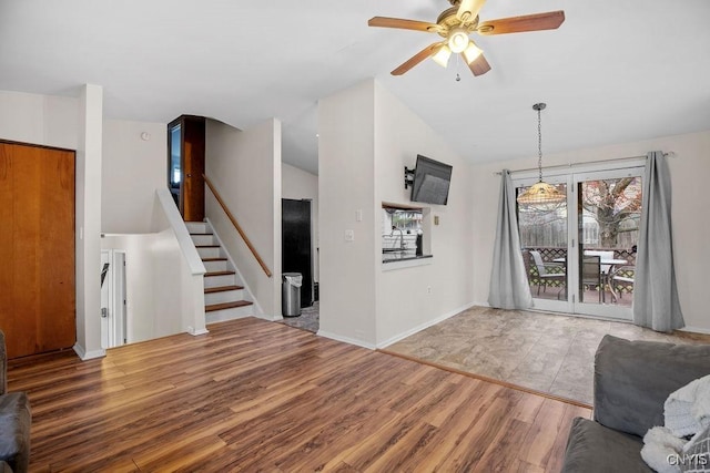 unfurnished living room featuring wood finished floors, ceiling fan, stairway, lofted ceiling, and baseboards