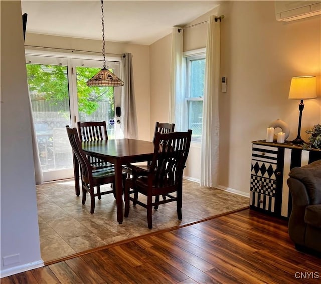 dining room with an AC wall unit, wood finished floors, and baseboards