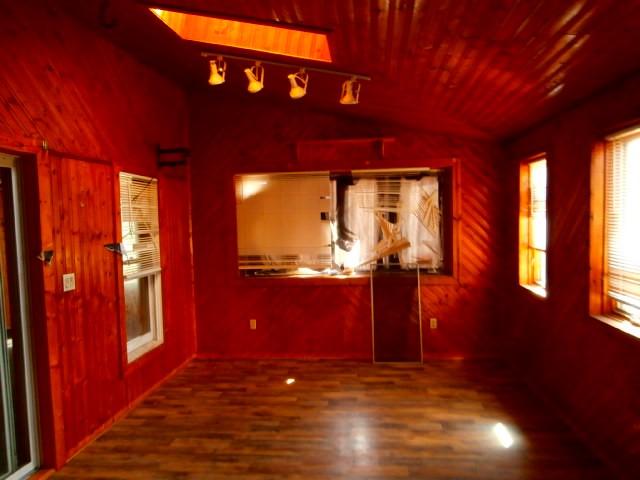 interior space with lofted ceiling, wood finished floors, and wooden walls