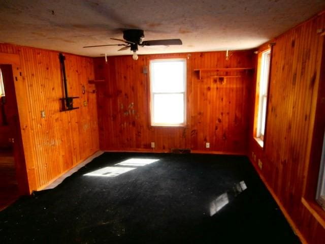 unfurnished room featuring a ceiling fan and wood walls