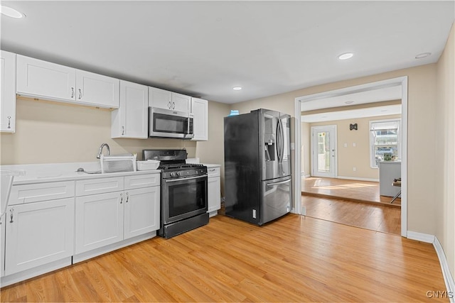 kitchen featuring light countertops, light wood-style flooring, appliances with stainless steel finishes, and white cabinets