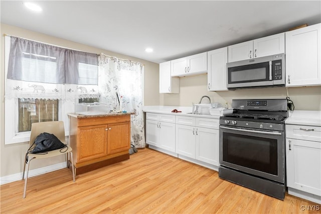 kitchen featuring light countertops, white cabinetry, appliances with stainless steel finishes, light wood-style flooring, and recessed lighting
