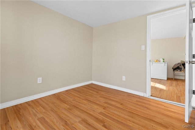 empty room with baseboards and light wood-style floors