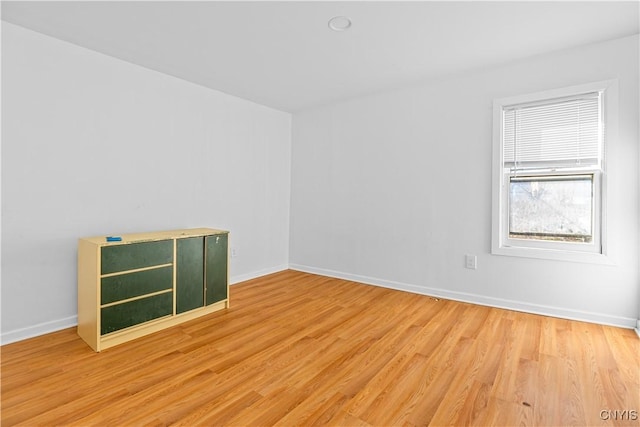 spare room featuring baseboards and light wood-type flooring