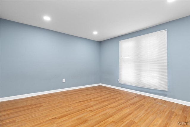spare room with baseboards, light wood-style floors, and recessed lighting