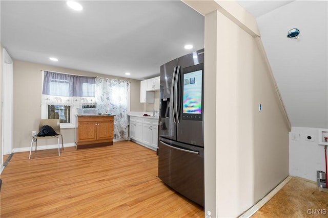 kitchen featuring light countertops, light wood finished floors, stainless steel fridge, white cabinets, and recessed lighting