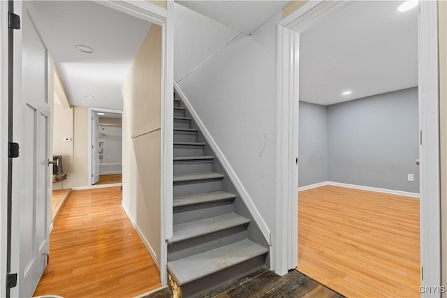 stairs with baseboards, wood finished floors, and recessed lighting