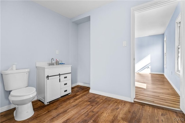 bathroom with baseboards, wood finished floors, toilet, and vanity