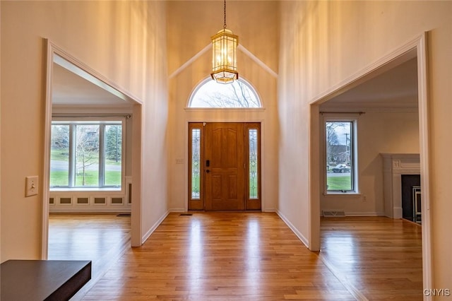 entryway with baseboards, a towering ceiling, and wood finished floors