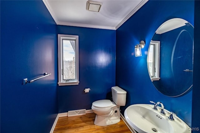 half bath featuring a sink, ornamental molding, and visible vents