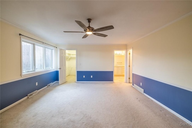spare room featuring a ceiling fan, crown molding, carpet, and visible vents