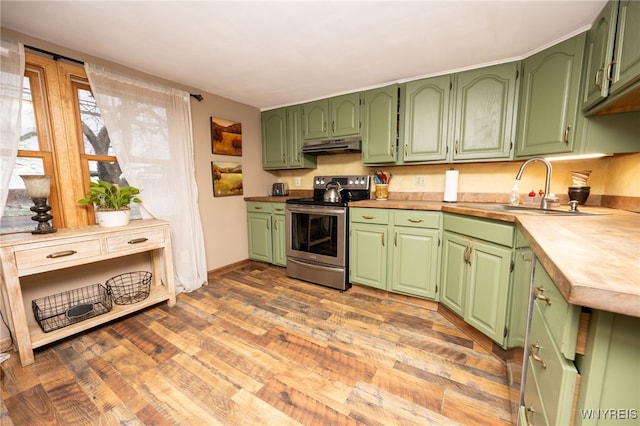 kitchen featuring light wood finished floors, under cabinet range hood, a sink, baseboards, and electric range