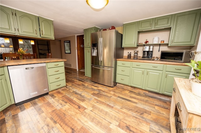 kitchen featuring light wood-type flooring, stainless steel appliances, a toaster, and green cabinets