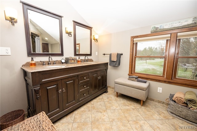 bathroom with lofted ceiling, tile patterned flooring, a sink, and double vanity