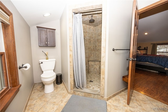 ensuite bathroom featuring toilet, baseboards, connected bathroom, and a stall shower