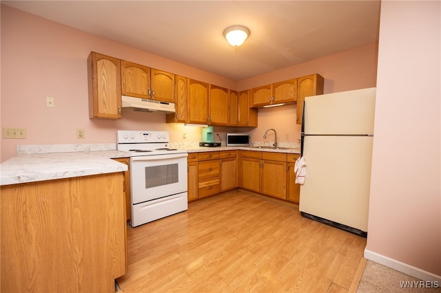kitchen featuring a sink, white appliances, light wood finished floors, light countertops, and under cabinet range hood