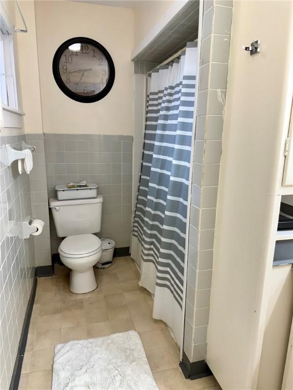 35 Sand St, Afton, NY 13730 - bathroom featuring toilet, tile patterned flooring, a wainscoted wall, and tile walls