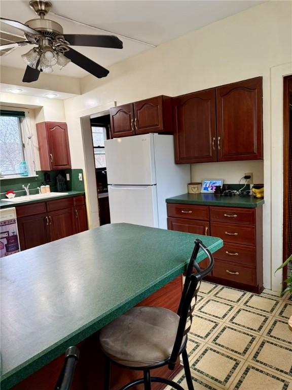 35 Sand St, Afton, NY 13730 - kitchen with a breakfast bar, freestanding refrigerator, dark countertops, ceiling fan, and a sink