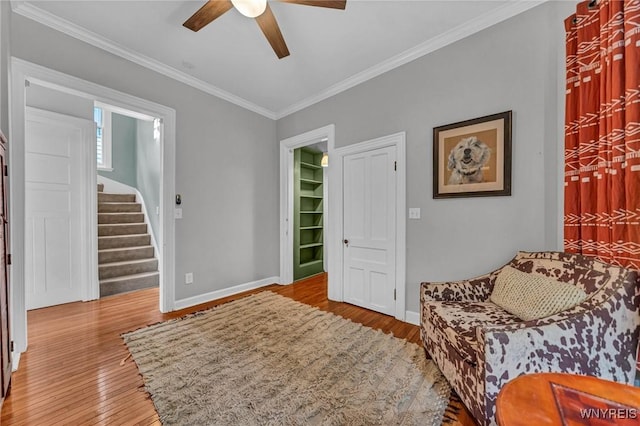 living area featuring ceiling fan, wood finished floors, stairs, baseboards, and ornamental molding