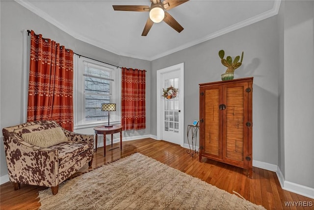 sitting room featuring baseboards, a ceiling fan, hardwood / wood-style floors, and ornamental molding