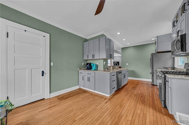 kitchen featuring stainless steel appliances, gray cabinetry, baseboards, light wood finished floors, and ornamental molding