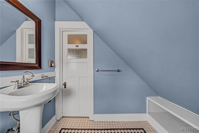 bathroom featuring lofted ceiling, baseboards, and a sink