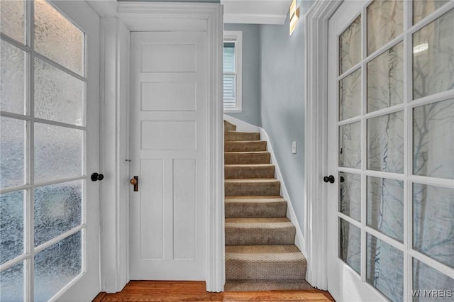 stairs with wood finished floors and french doors