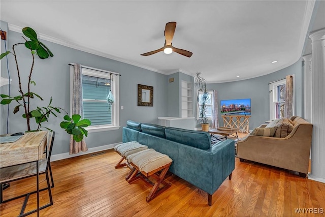 living room featuring wood-type flooring, a ceiling fan, ornamental molding, and baseboards